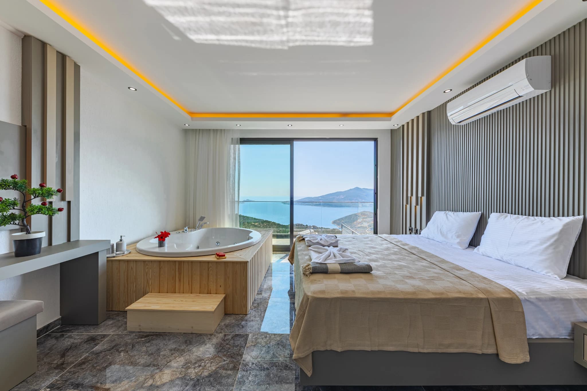 Luxurious master bedroom with sea-view jacuzzi tub and mountain vista from private balcony.