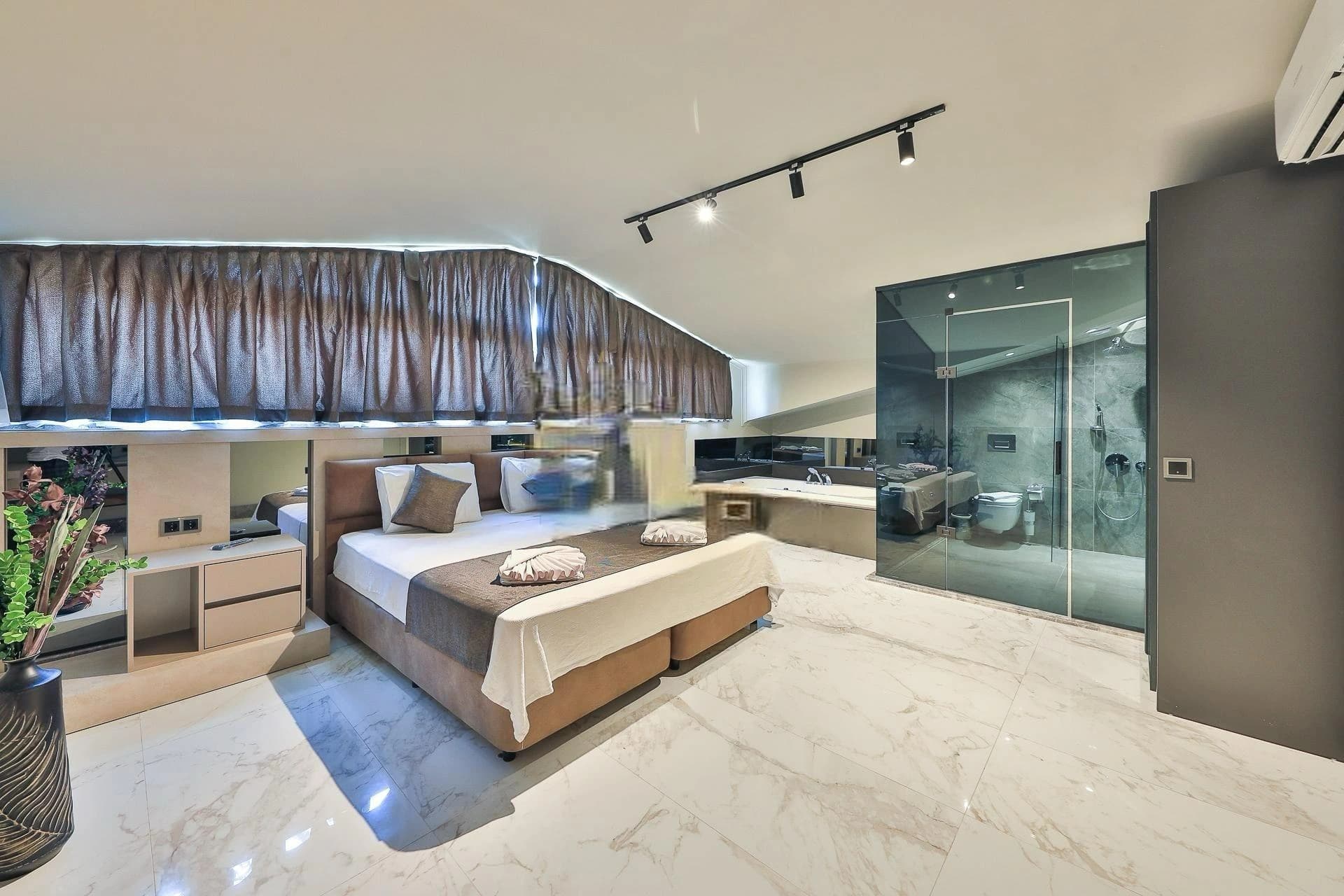 Contemporary bedroom with double bed and en-suite bathroom featuring glass walk-in shower.