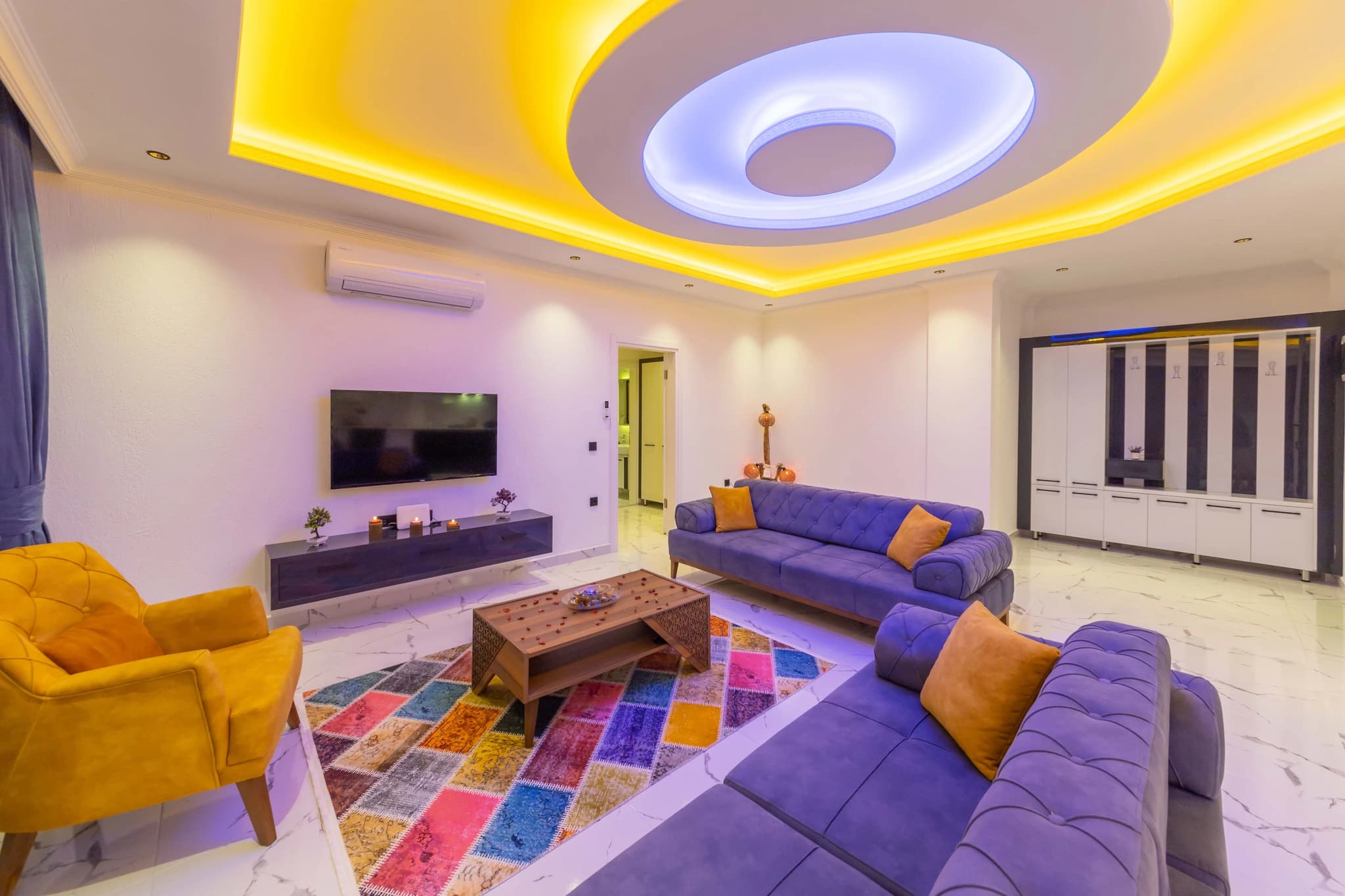 Secluded Garden Villa with Private Pool and Mountain Views in Kalkan – Spacious living room with purple and yellow seating, LED accent ceiling, and contemporary décor.