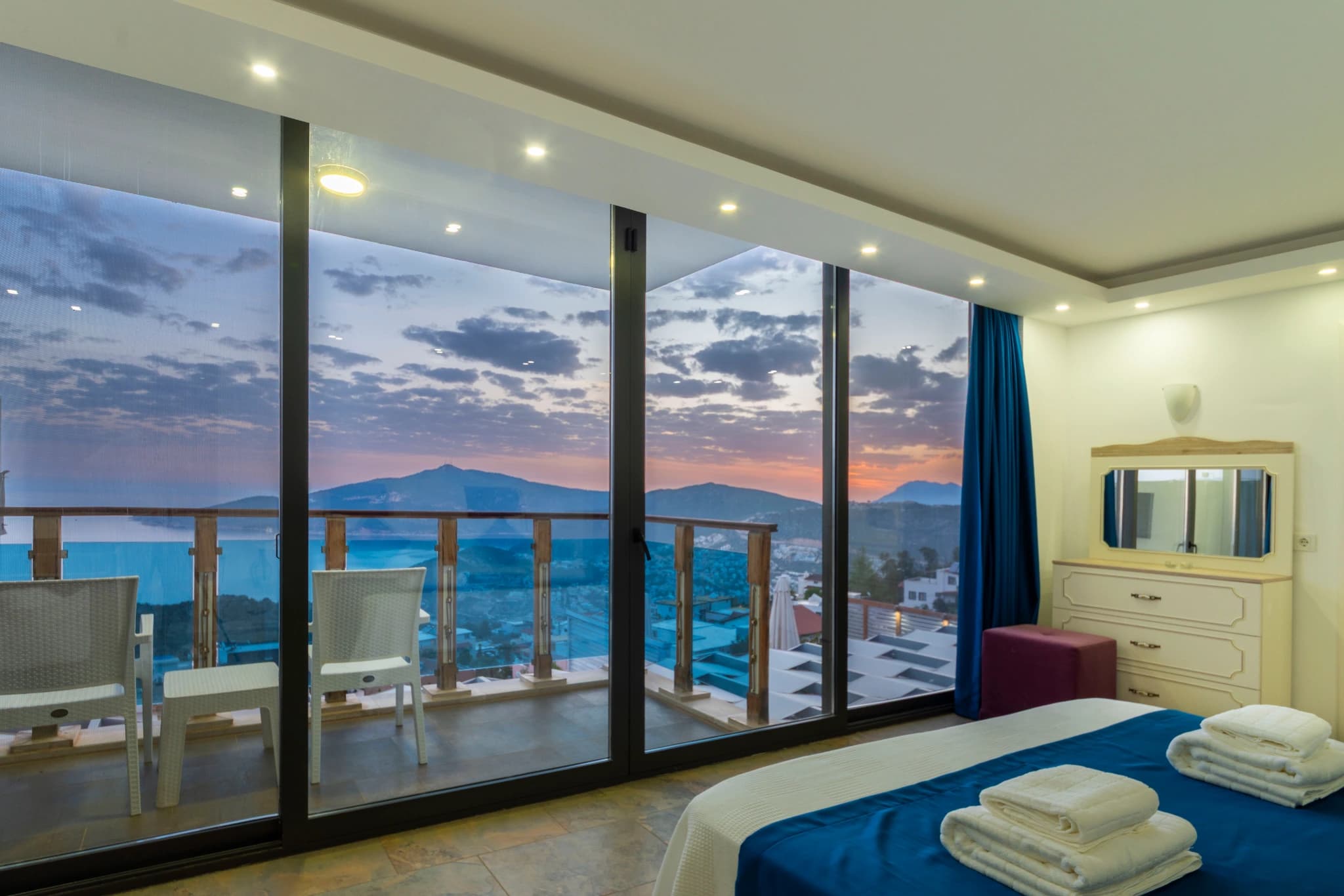 Premium bedroom with expansive sea and mountain views from private terrace.