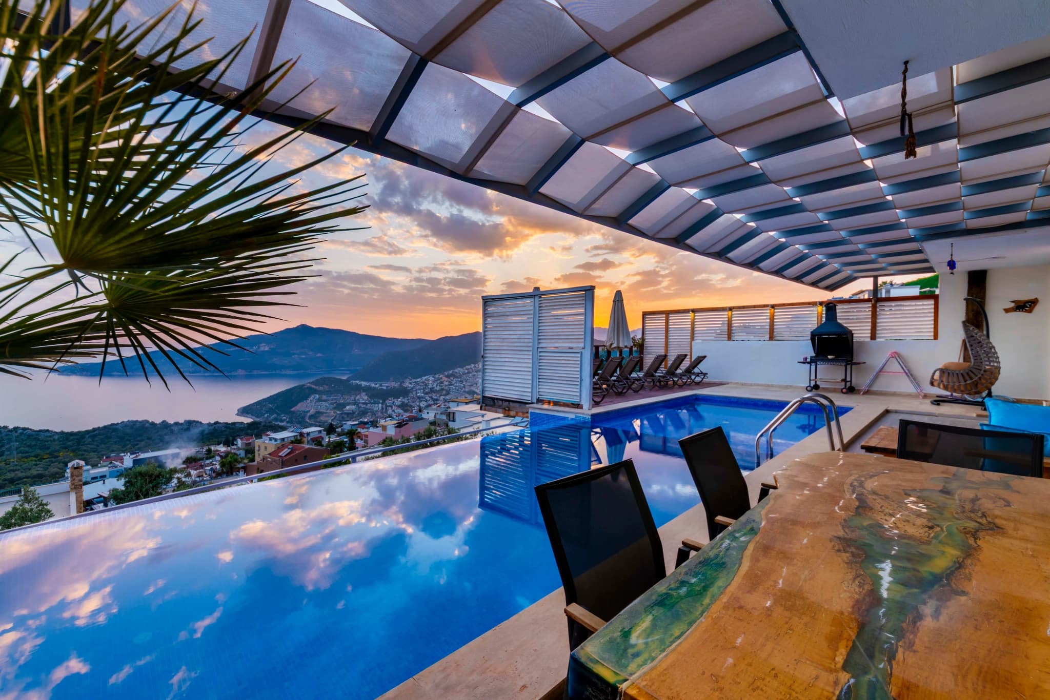 Stunning infinity pool with panoramic sea and mountain views at golden hour.