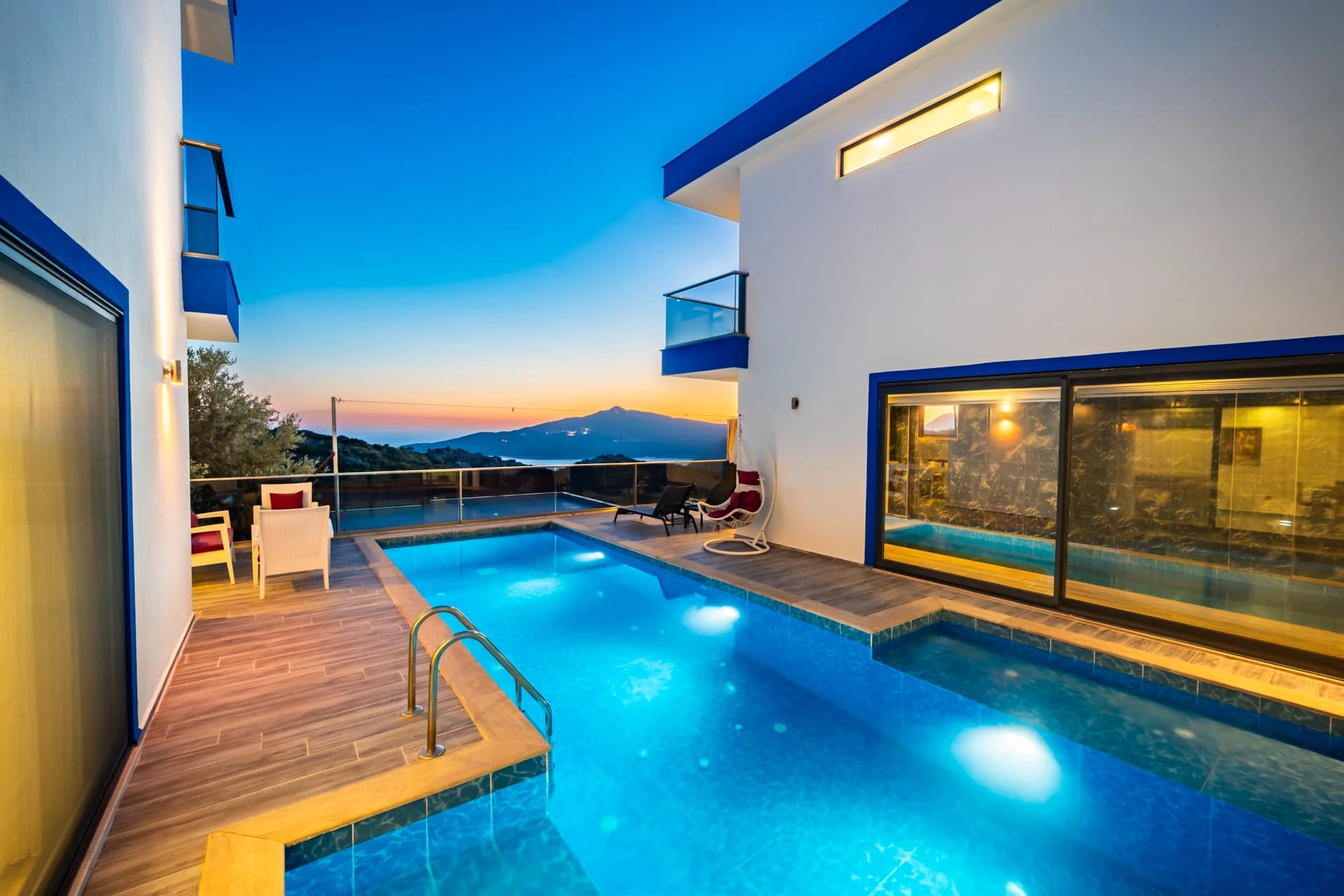 Stunning twilight view of illuminated private pool with mountain backdrop.
