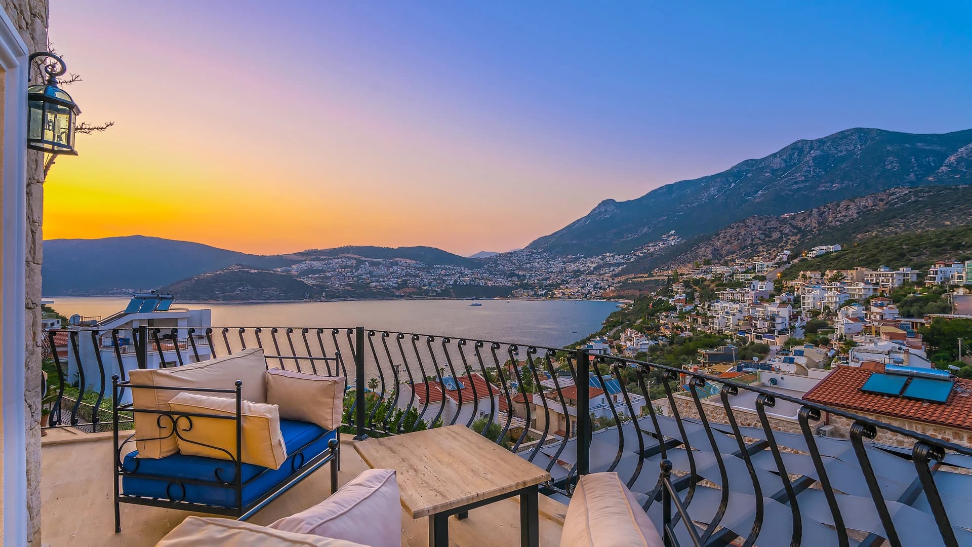 Breathtaking sunset terrace with lounge seating overlooking Mediterranean bay and hillside.