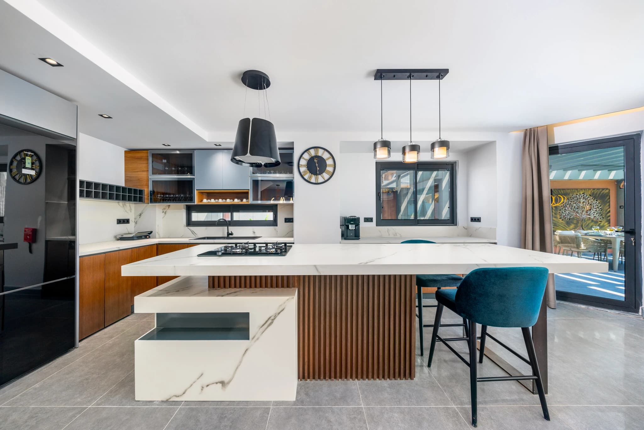 Modern chef's kitchen with marble island, professional gas cooktop, and access to outdoor terrace.