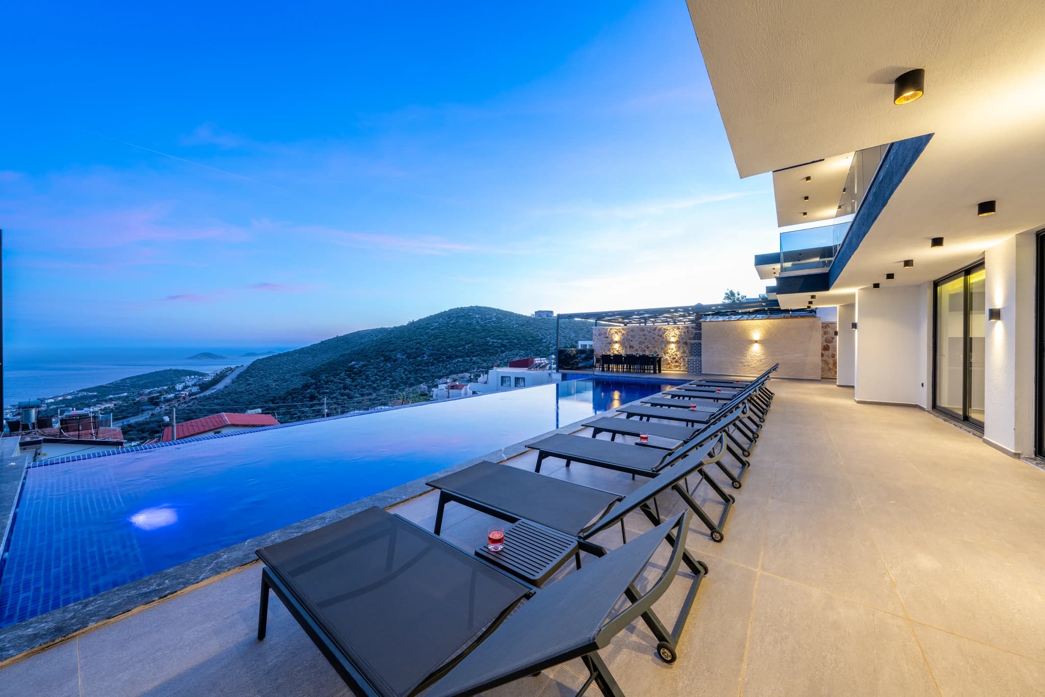 Elevated private pool with sea views, multiple sun loungers, and modern terraced architecture.