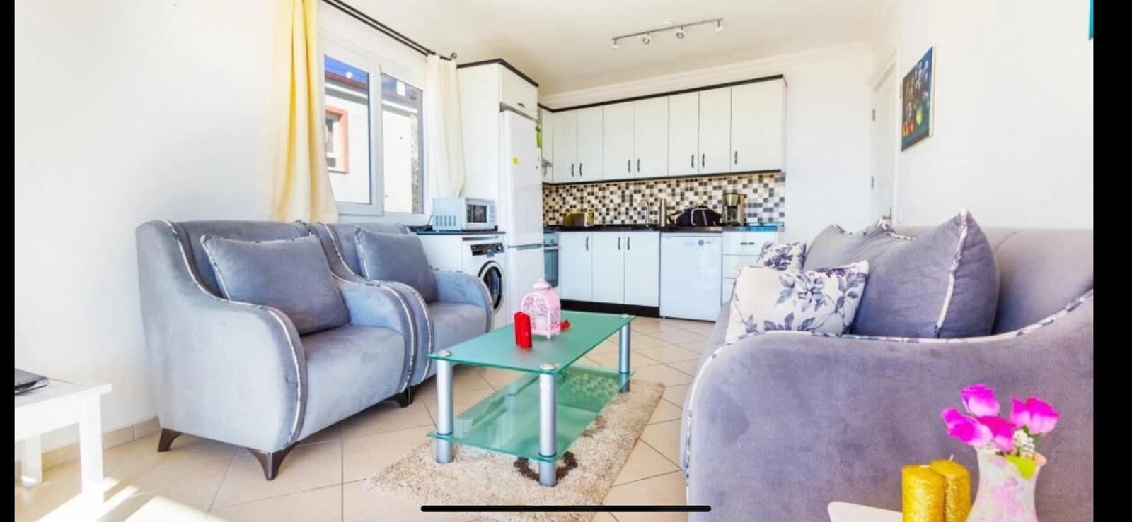 Living room with open-plan kitchen, comfortable seating, and natural light.