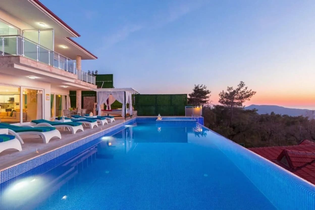 Breathtaking dusk pool scene with mountain backdrop and lounge seating.