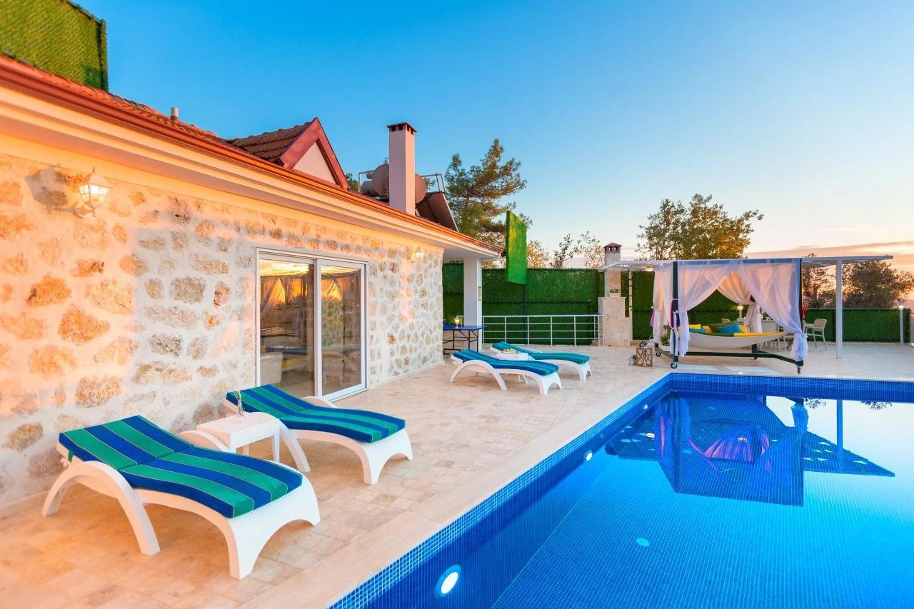 Stunning pool area with multiple sun loungers and covered terrace at sunset.