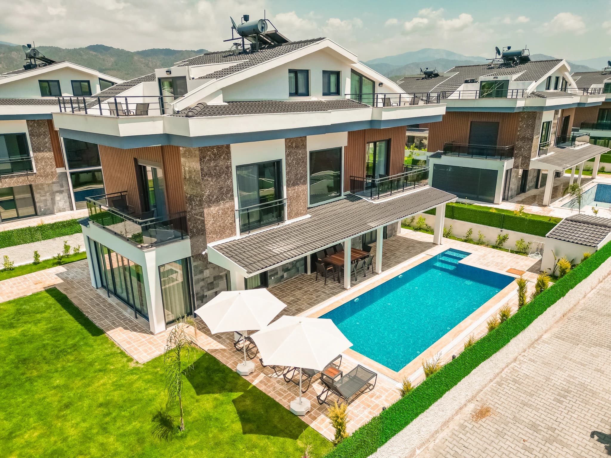 Aerial view of the villa with private pool, landscaped garden, and mountain backdrop.