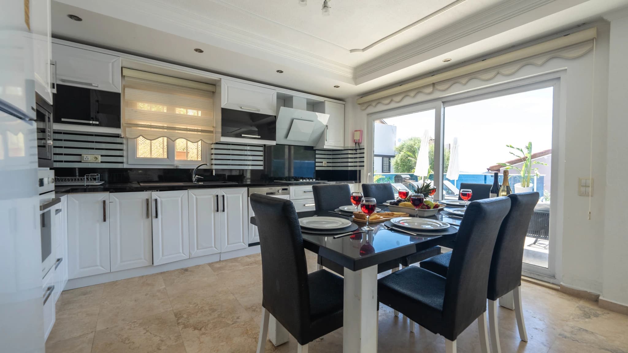 Contemporary open-plan kitchen and dining area with pool views and modern appliances.