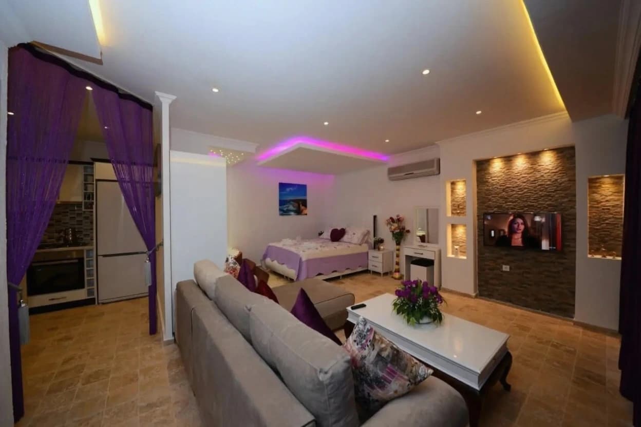 Modern studio bedroom with open-plan layout, purple-themed décor, and contemporary furnishings.