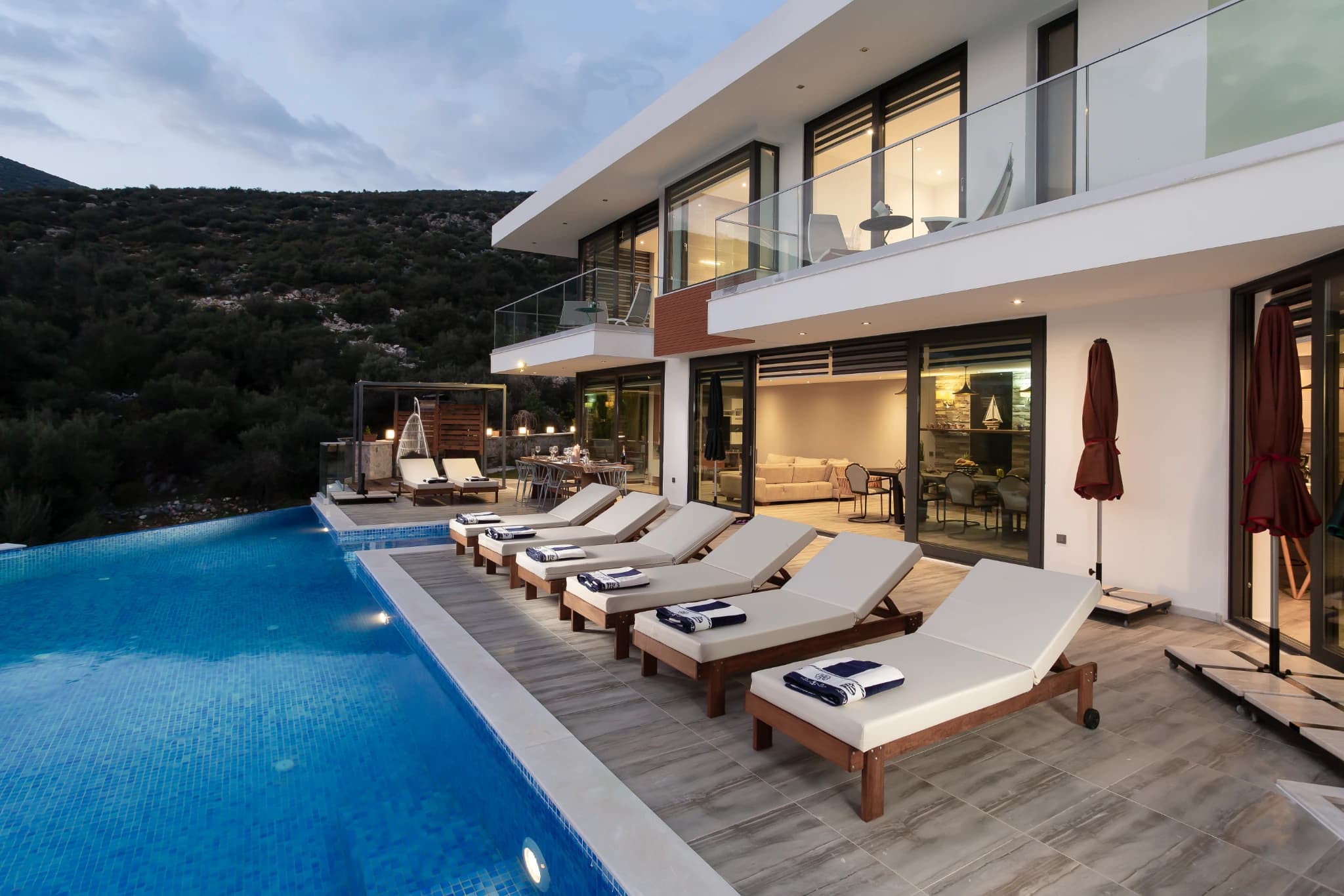 Private pool with sun loungers overlooking mountains and garden landscape.