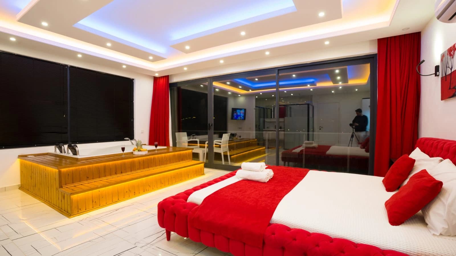 Master bedroom with stylish red upholstered bed and integrated bar counter.