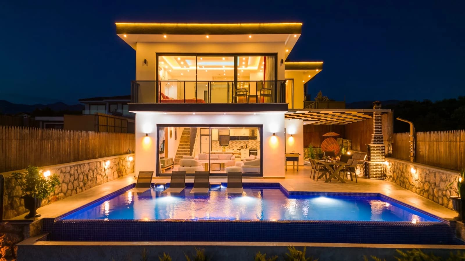 Beautifully lit swimming pool at dusk with comfortable loungers, perfect for evening relaxation and stargazing.