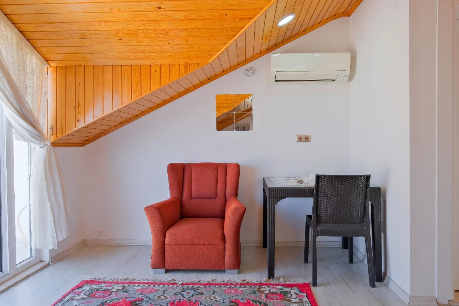 Cozy reading nook with red armchair and modern amenities.
