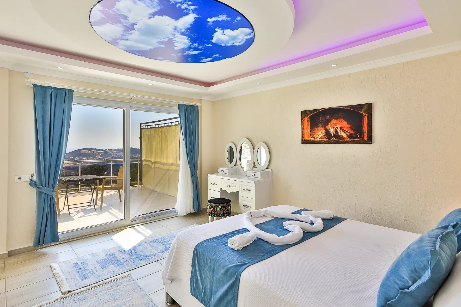 Bedroom with queen bed, private balcony overlooking mountains, and fireplace accent.