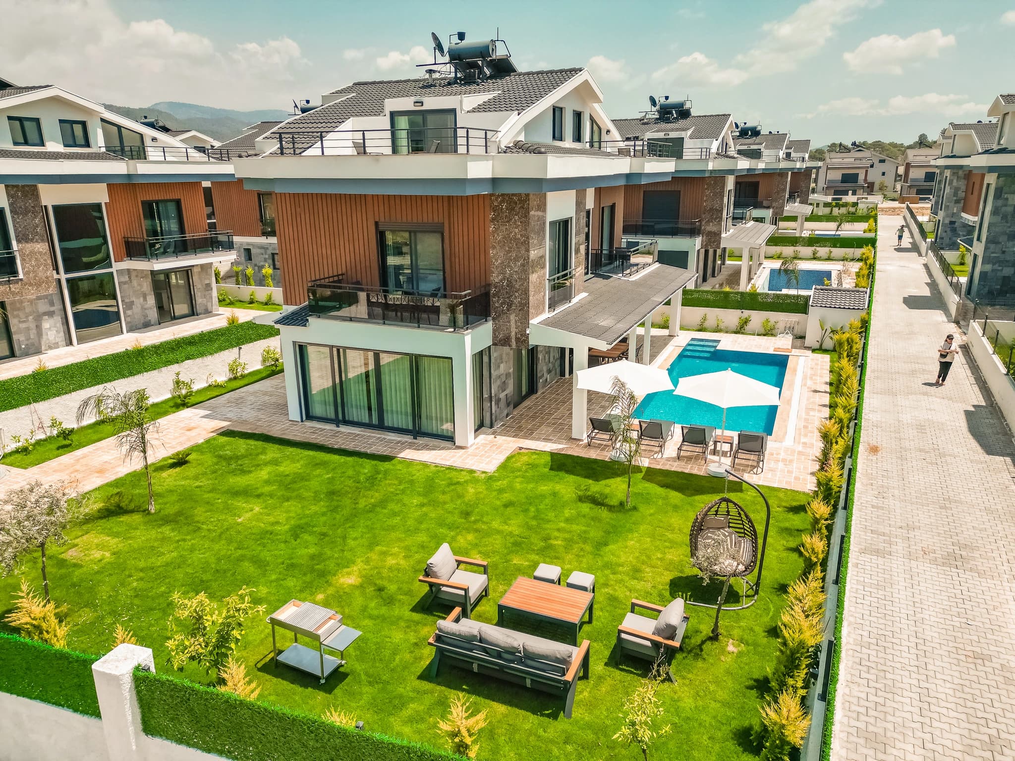 Contemporary villa exterior showing three-story design with pool and illuminated landscaping.