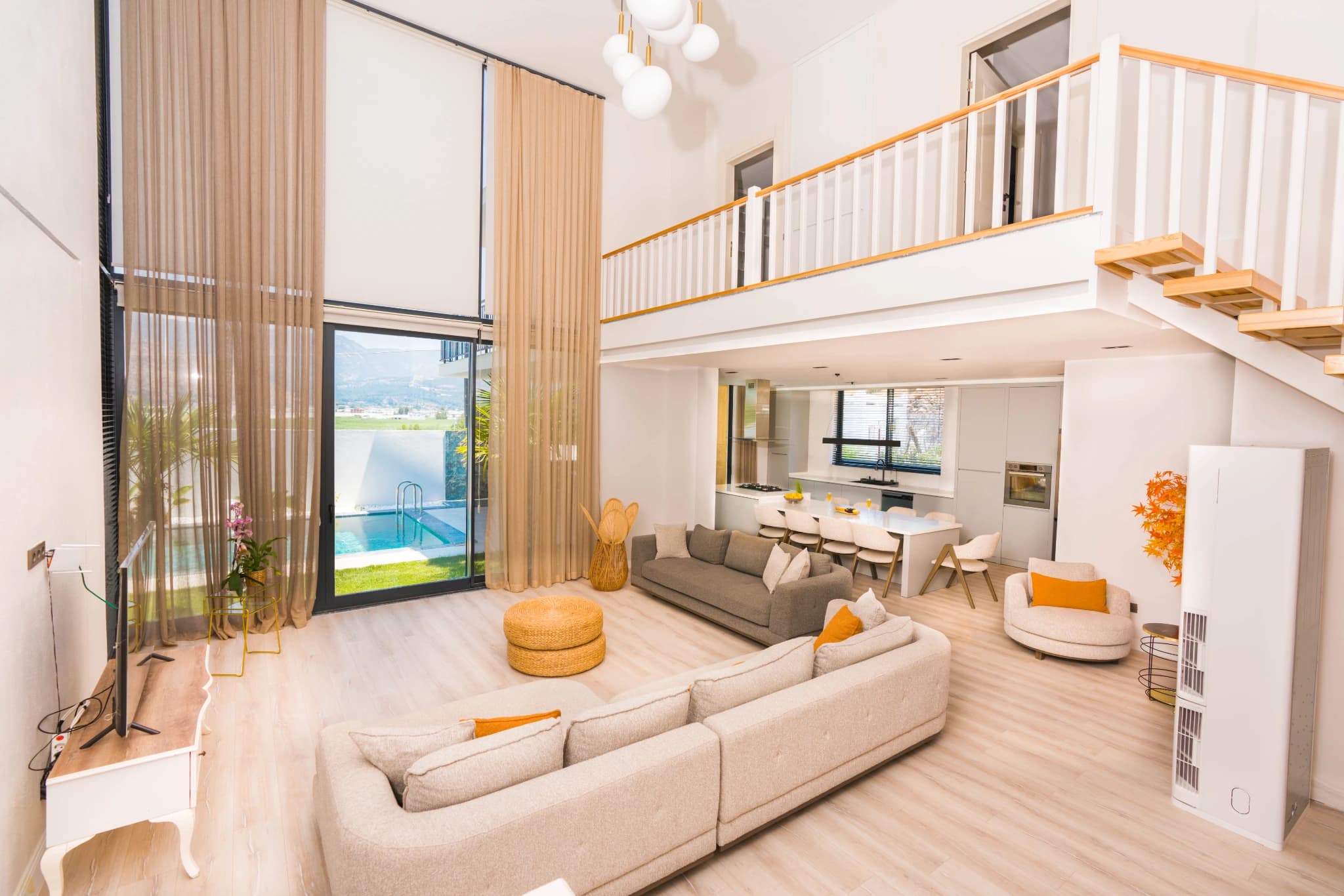 Spacious double-height living room with pool and sea views through floor-to-ceiling windows.
