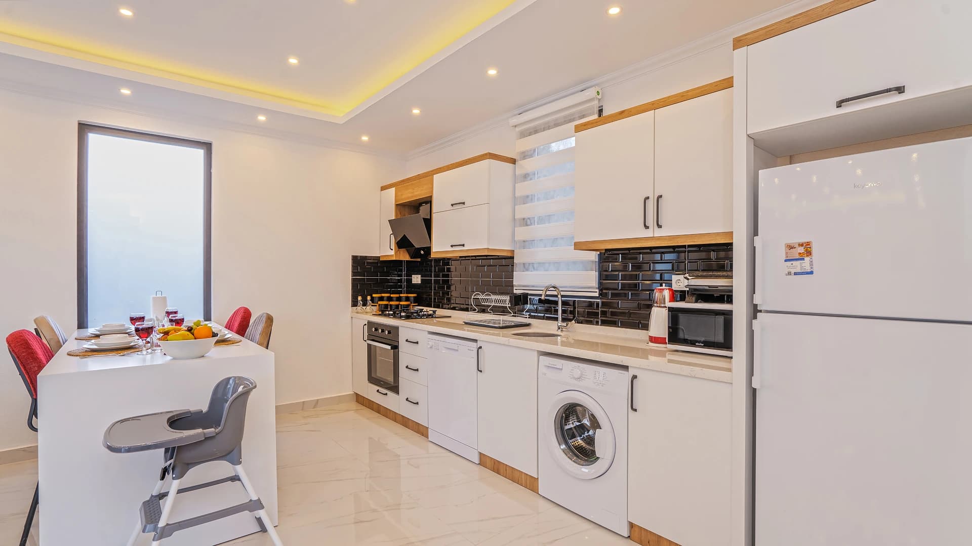 Contemporary kitchen with integrated dining space, stainless steel appliances, and natural wood accents.