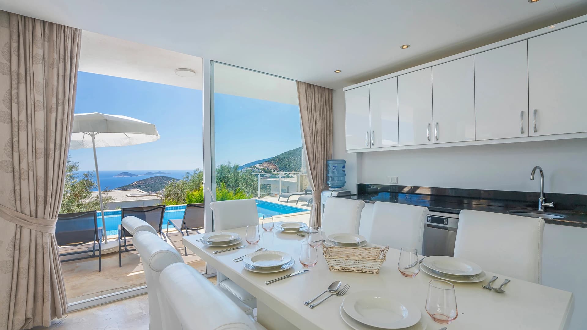 Open-plan dining area with sea and mountain views, direct terrace access to pool.