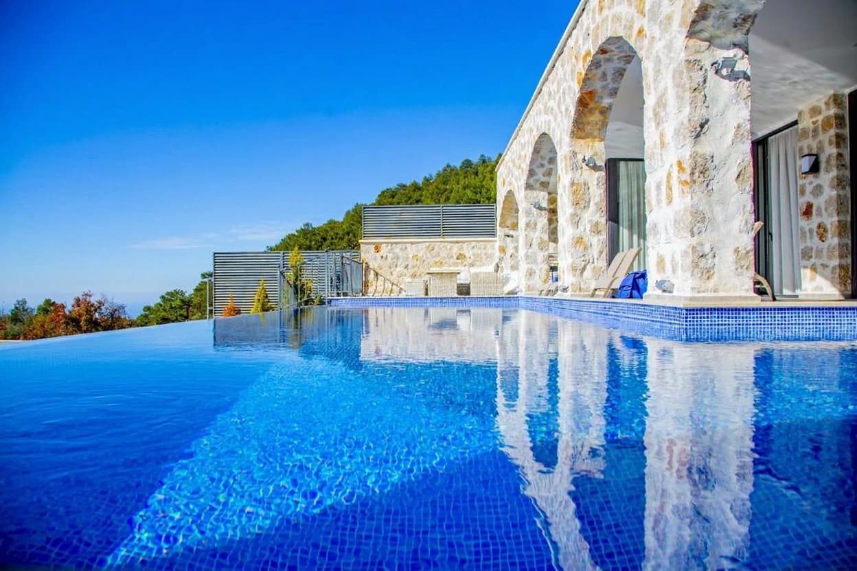 Stunning infinity pool with panoramic mountain views and modern stone architecture.