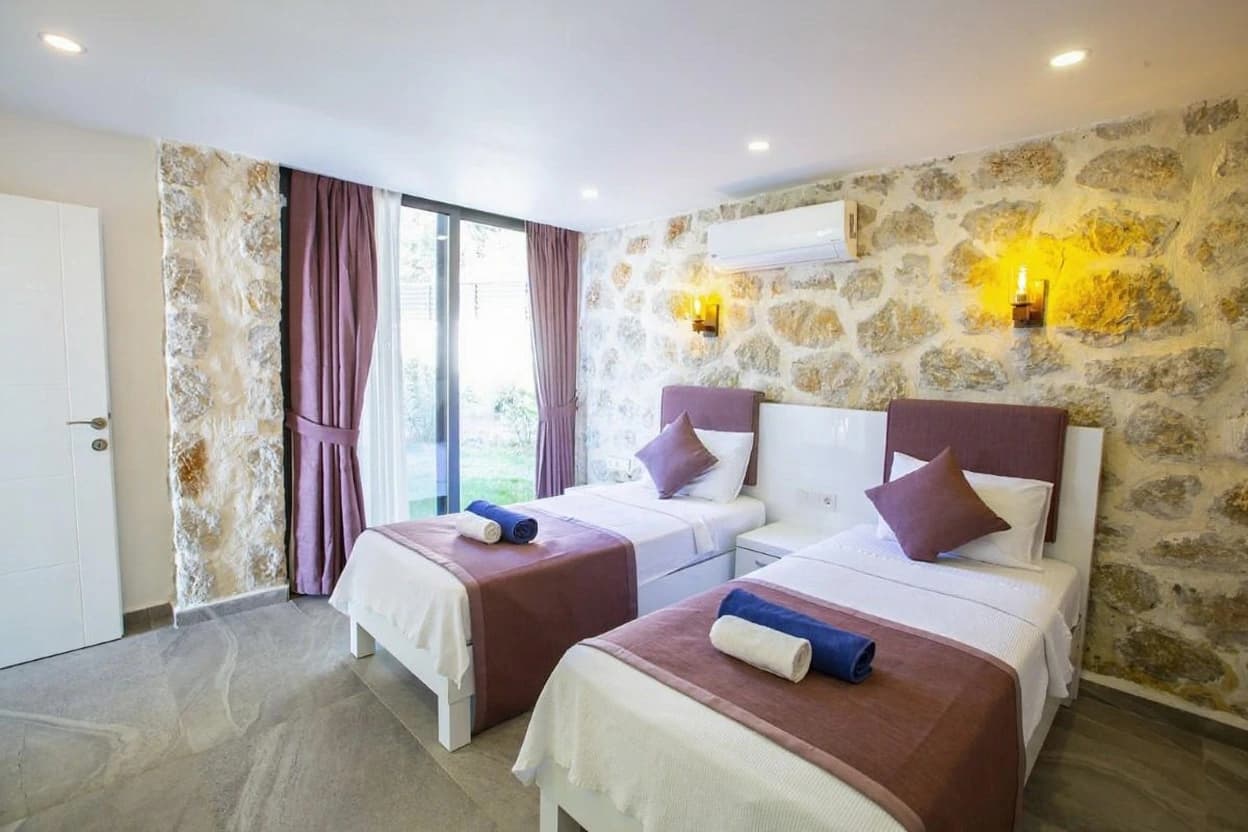 Spacious twin bedroom with rustic stone walls and garden access.