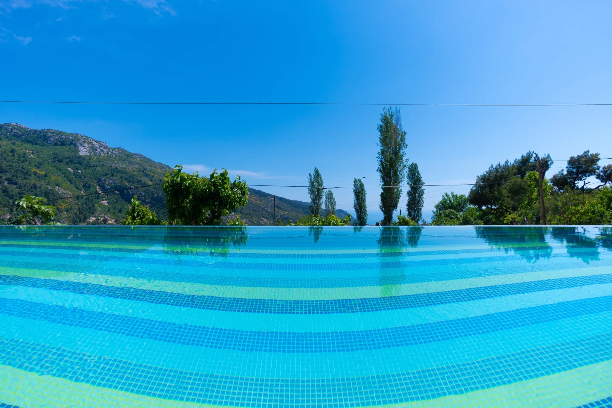 Serene private pool with mountain backdrop and clear blue water.