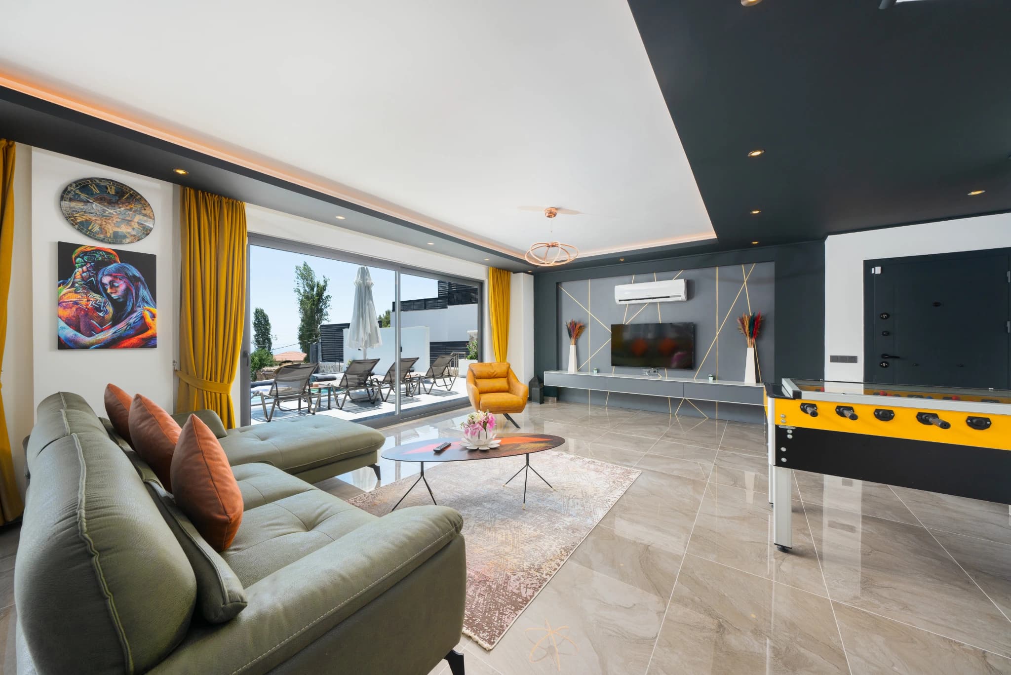 Spacious modern living room with sofa, entertainment system, foosball table, and terrace views.