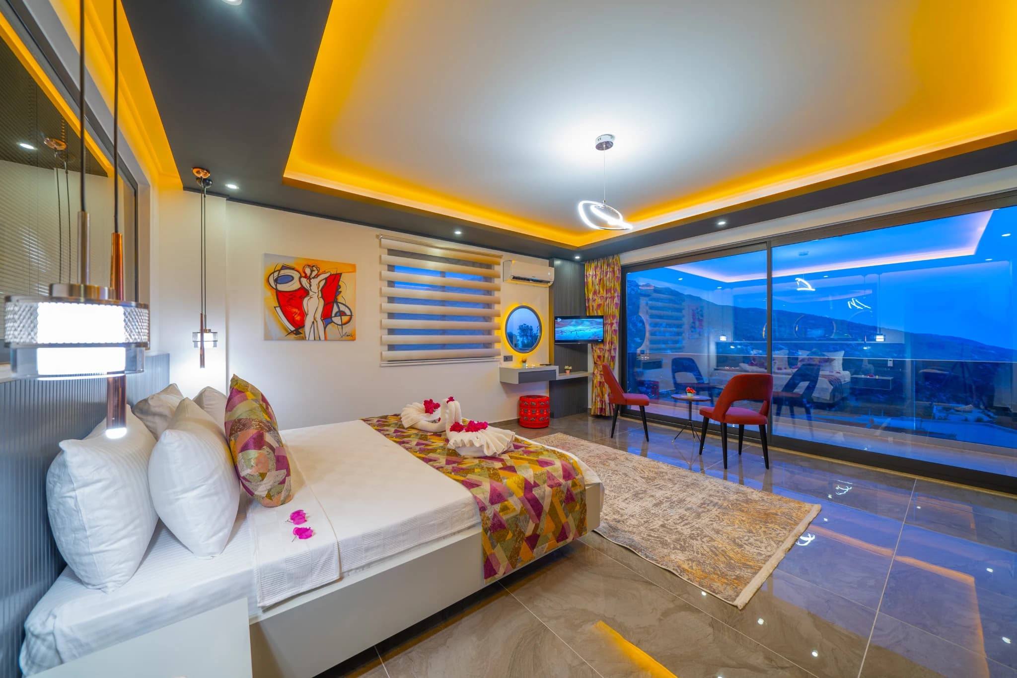 Spacious master bedroom with king bed and expansive balcony overlooking the city at dusk.