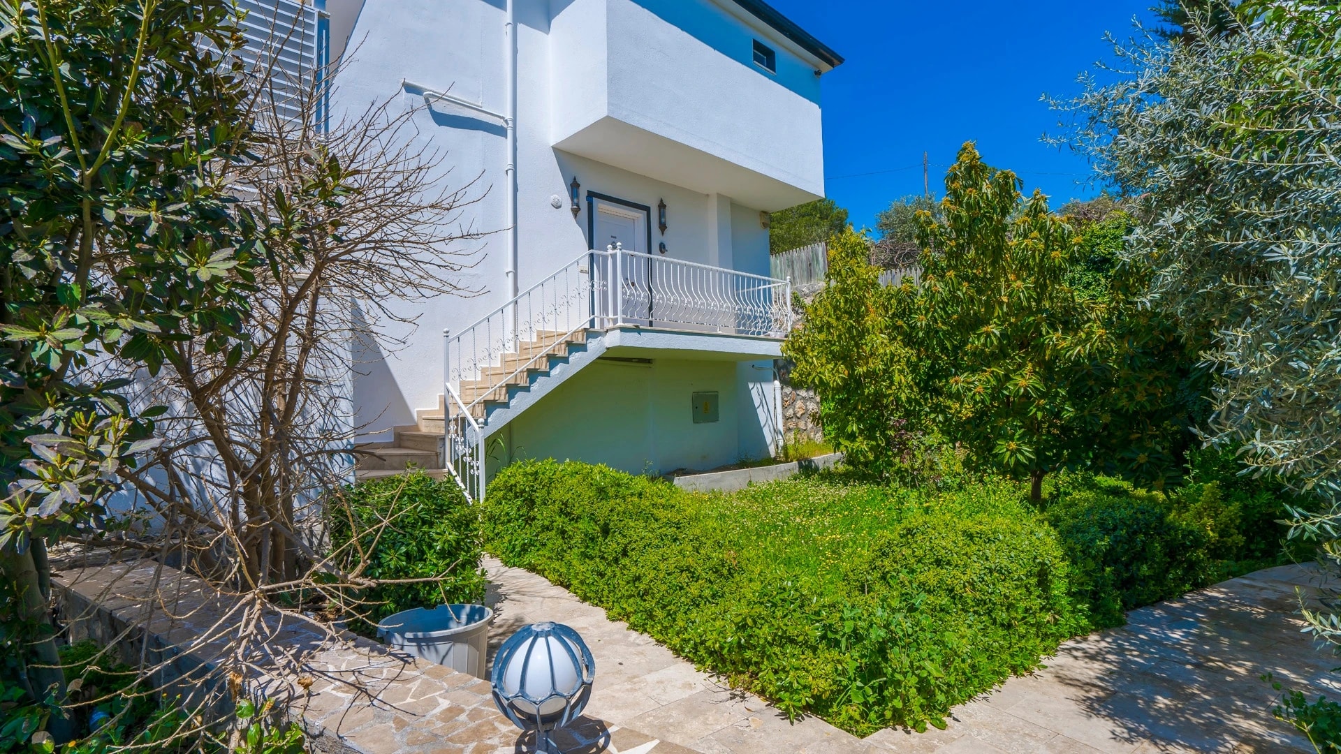 Secluded Nature Retreat Villa with Heated Pool and Sea & Mountain Views in Kalkan – Modern villa exterior with white and blue contemporary design surrounded by lush greenery.