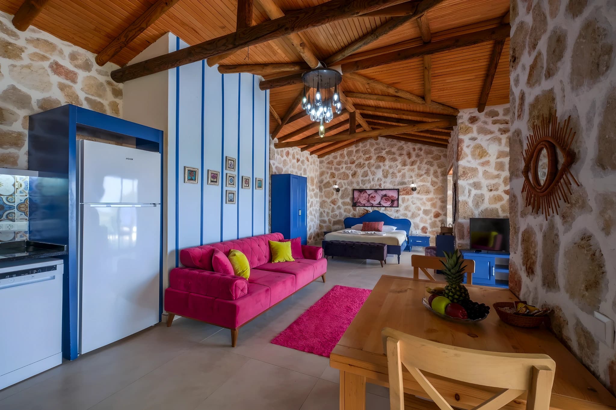 Spacious open-plan living area with vibrant magenta sofa and rustic wooden ceiling.