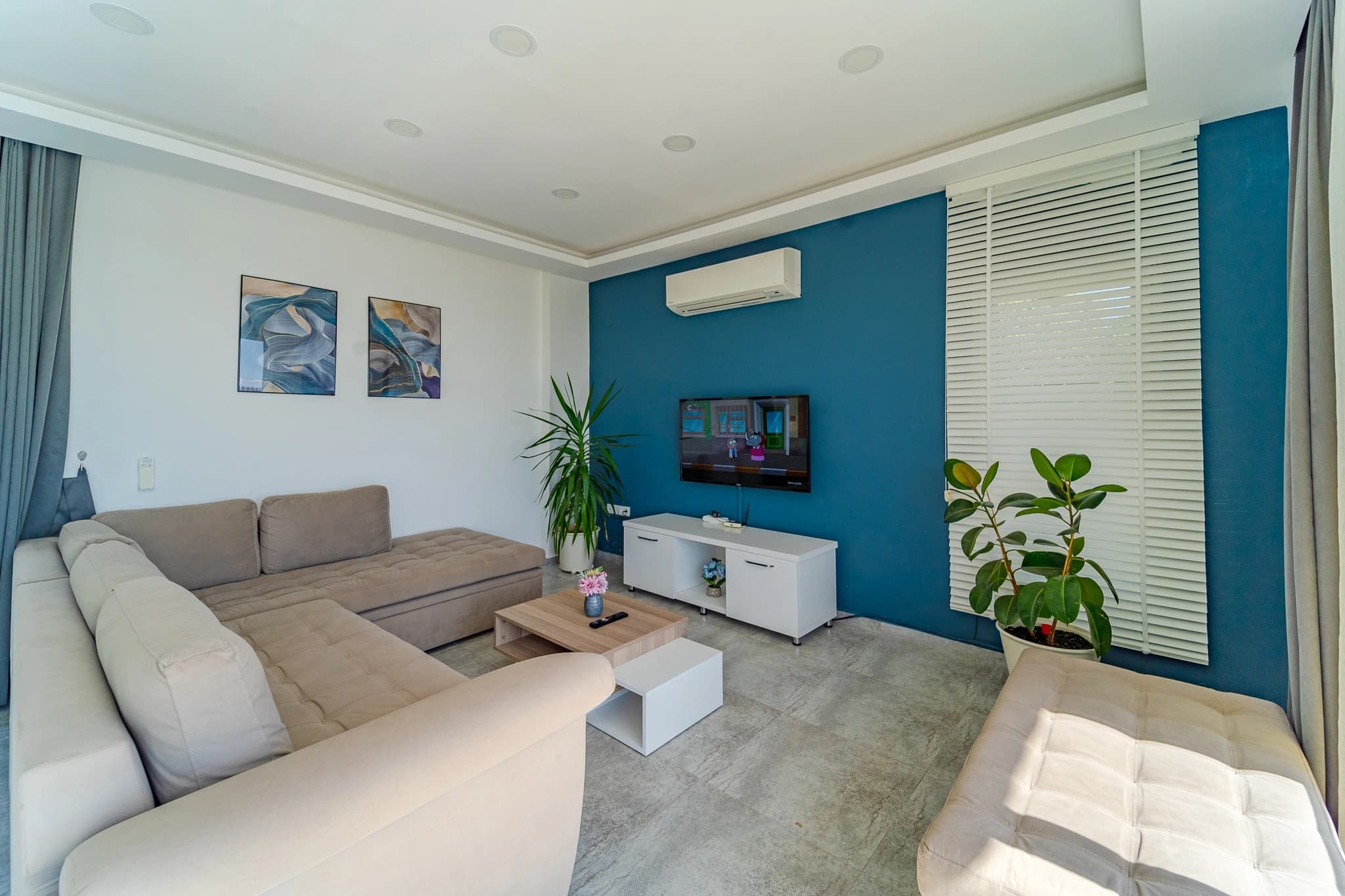 Abgeschiedene 2-Zimmer-Villa mit Infinity-Pool und Bergblick bei Kalkan – Modern living room with teal accent wall, comfortable sectional seating, and contemporary furnishings.
