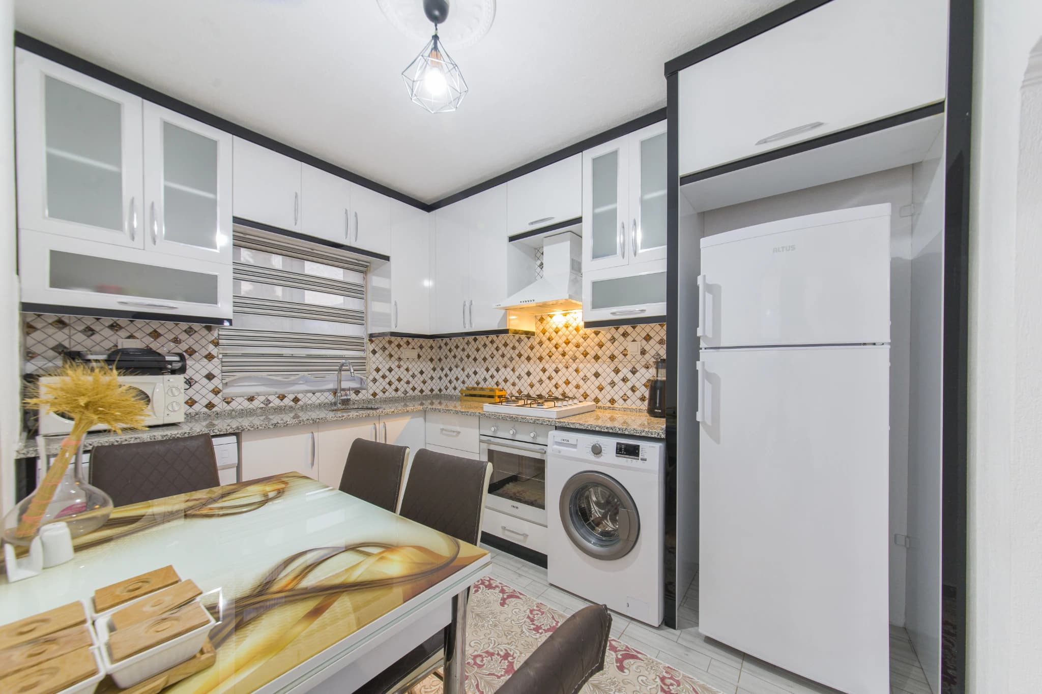 Wide-angle view of the kitchen-dining space with white cabinetry and checkerboard accents.