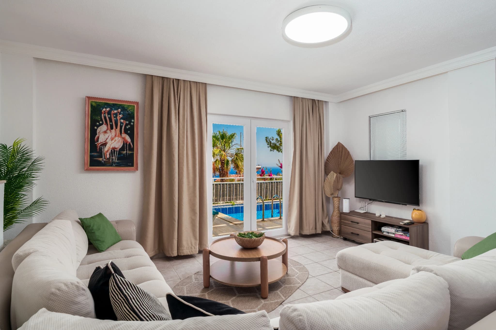 Spacious living room with sea and pool views through glass doors, comfortable seating, and TV.