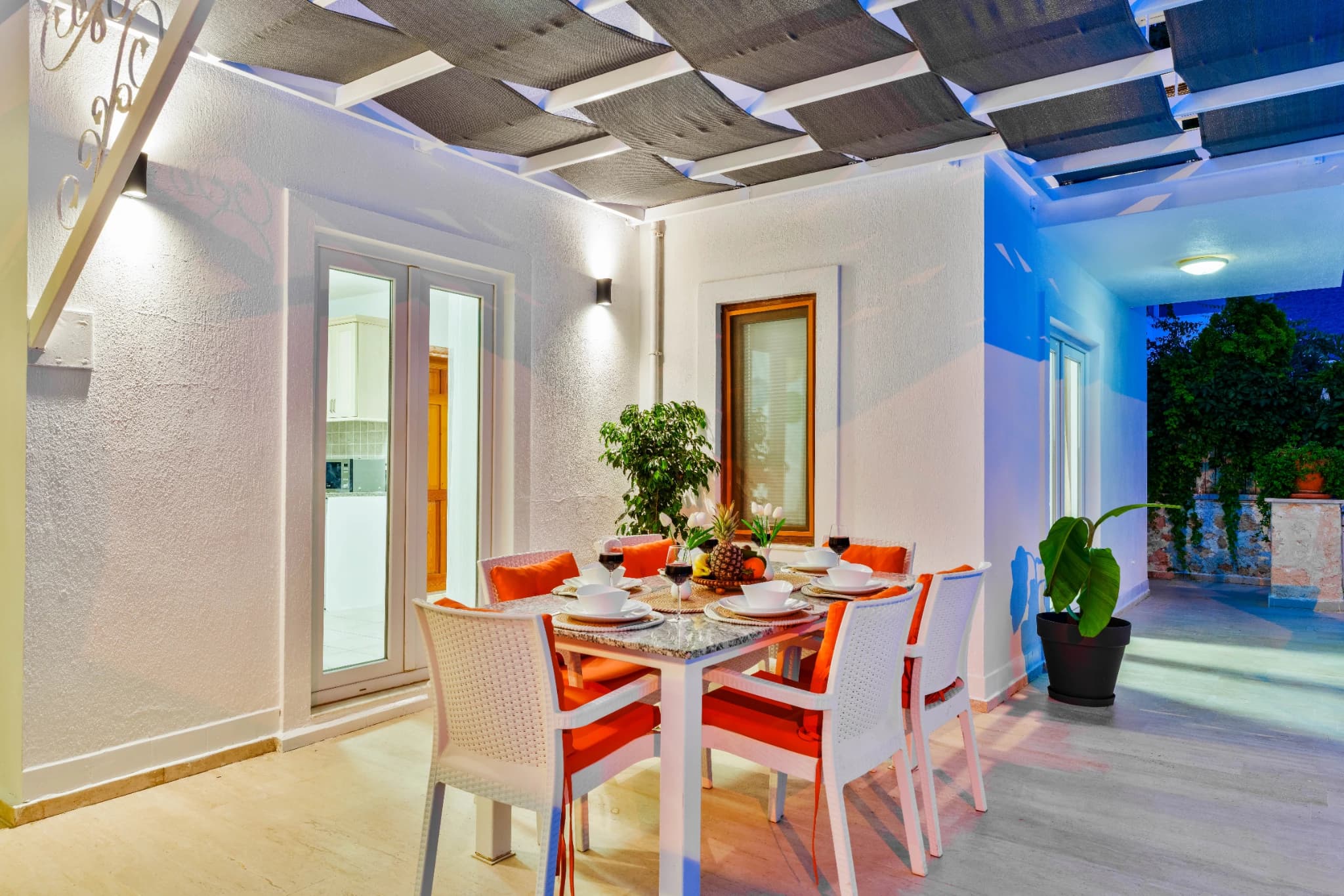 Modern dining area with orange-accented chairs and open access to outdoor spaces.