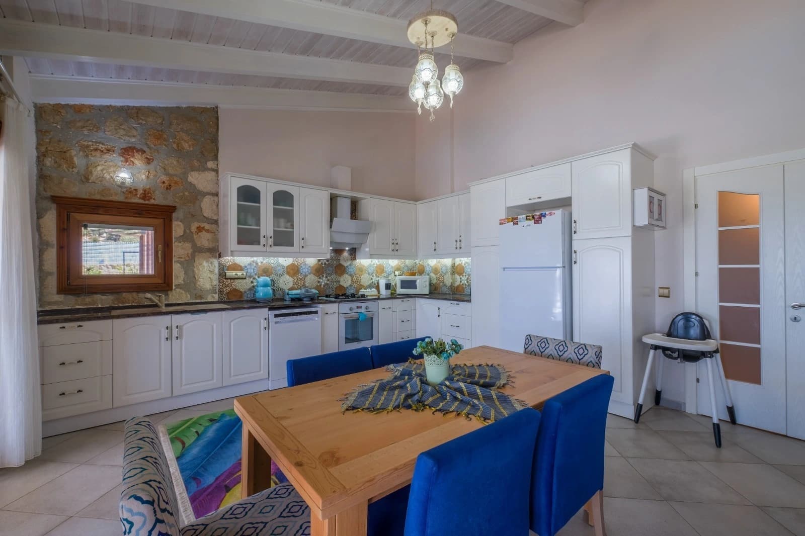 Bright open-plan kitchen with white cabinetry and dining area featuring blue seating.