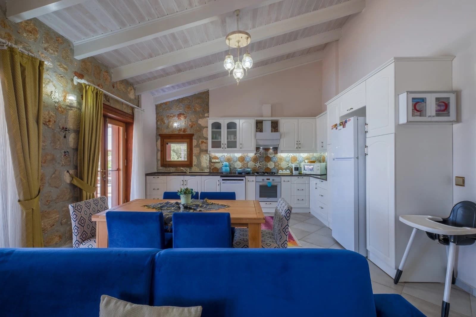 Spacious dining room with rustic stone walls and contemporary blue dining chairs.