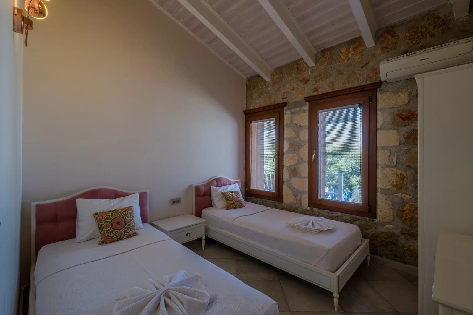 Twin bedroom with rustic stone walls and outdoor access.