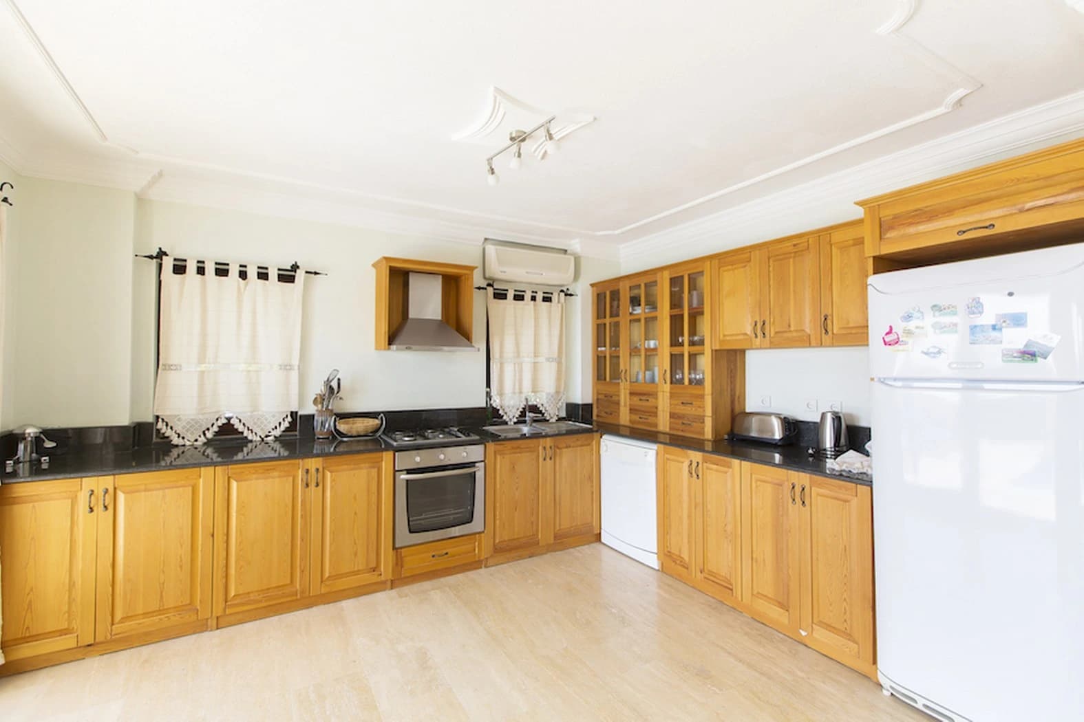 Spacious kitchen with wooden cabinetry, gas cooktop, and modern appliances.