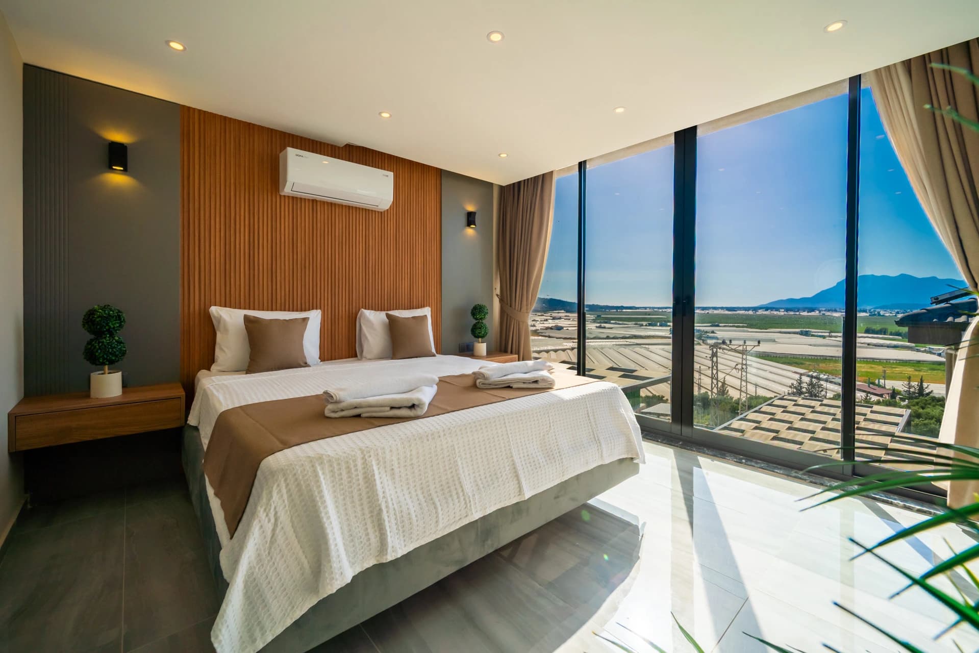 Luxurious bedroom with panoramic mountain and valley views through floor-to-ceiling windows.