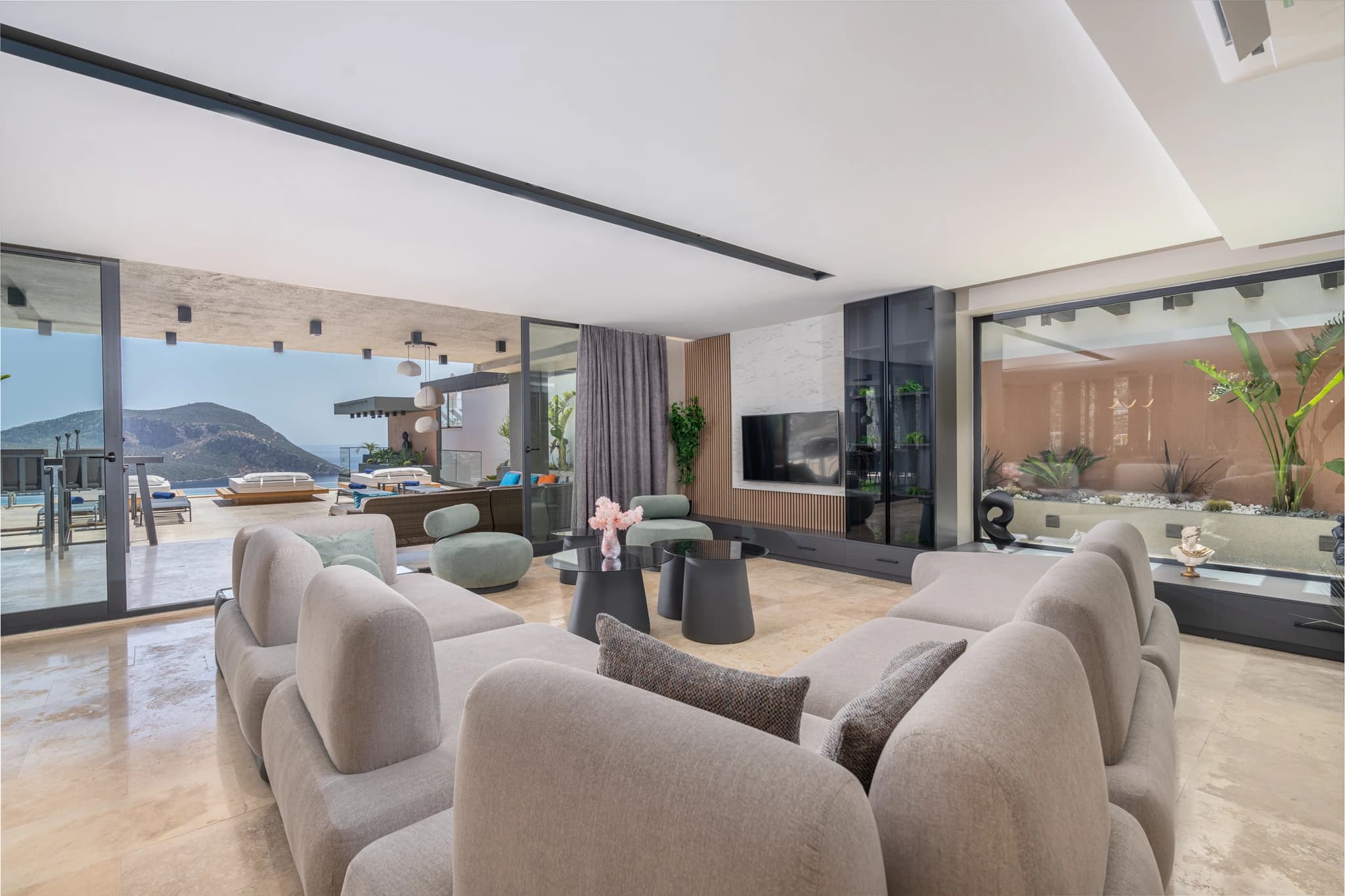 Contemporary open-plan living area with panoramic windows showcasing sea and mountain vistas.