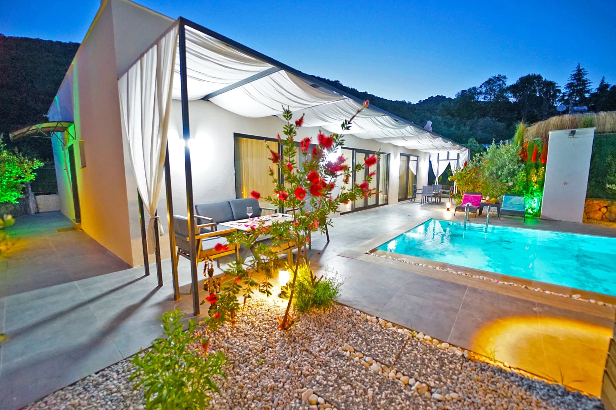 Modern villa exterior with private pool, terrace seating, and mountain backdrop.