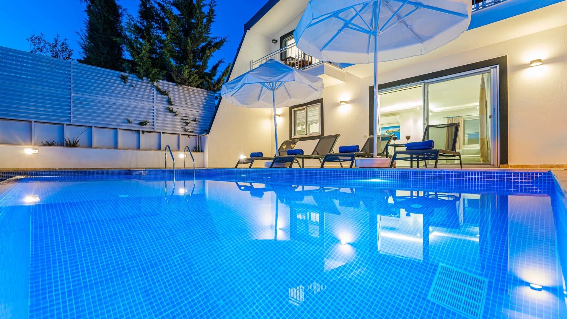 Abgeschiedene 2-Zimmer-Villa mit beheiztem Pool und Berg- & Meerblick in Kalkan – Crystalline pool at dusk with lounge chairs and pergola shade structure overlooking the property.