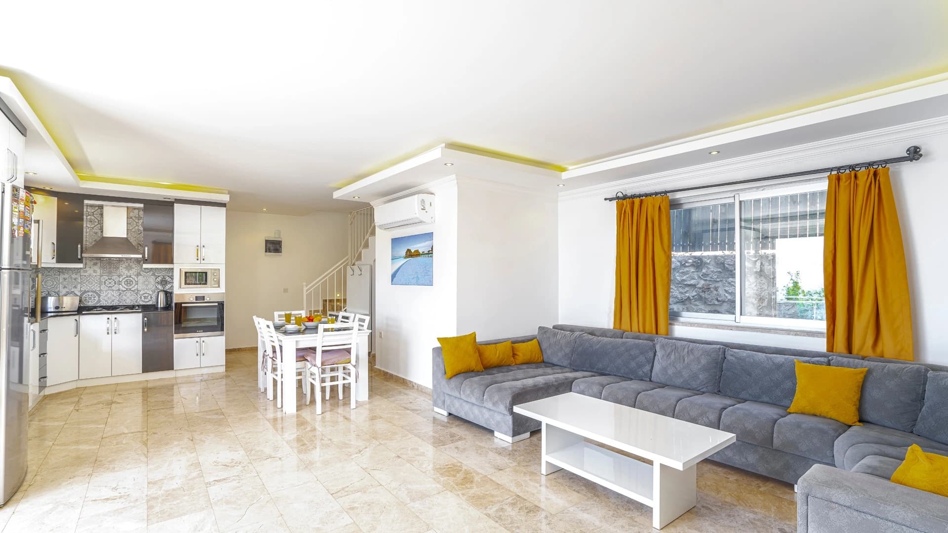 Abgeschiedene 2-Zimmer-Villa mit beheiztem Pool und Berg- & Meerblick in Kalkan – Contemporary living room with gray sectional sofa, yellow accessories, and integrated kitchen.