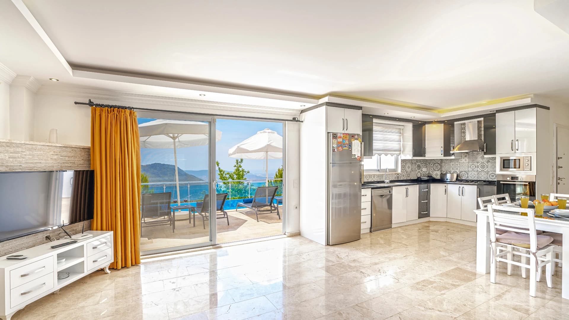 Abgeschiedene 2-Zimmer-Villa mit beheiztem Pool und Berg- & Meerblick in Kalkan – Spacious open-plan living and kitchen area with expansive sea views and access to terrace.