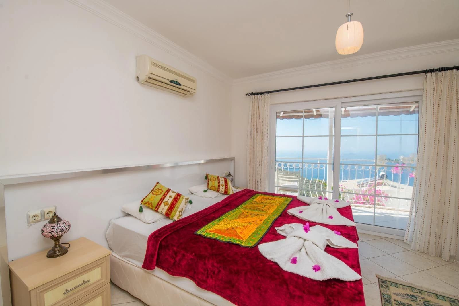 Spacious bedroom with queen bed and stunning sea view from private balcony.